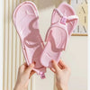 A pair of pink foldable EVA travel slippers being held by hands against a light background.