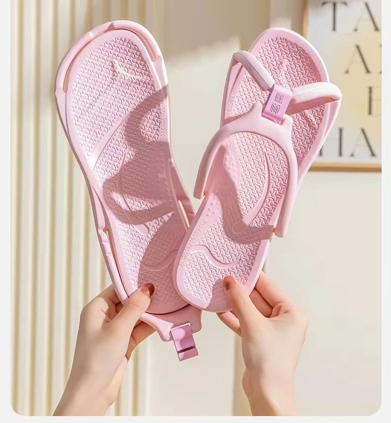 A pair of pink foldable EVA travel slippers being held by hands against a light background.