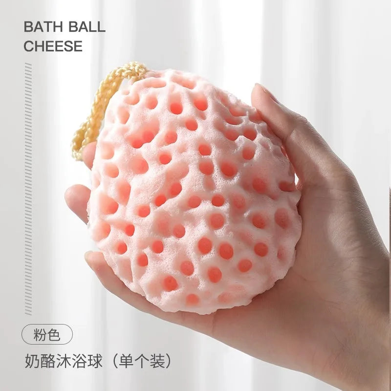 A hand is holding a pink bath ball cheese product, which is a soft mesh sponge for baby.