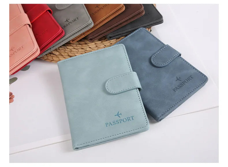 Une pile de porte-passeports en cuir de différentes couleurs, dont une bleu clair, posée sur une surface blanche.