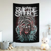 A black tapestry featuring a distressed, bloody face with long hair and intense eyes, rendered in white and red tones.