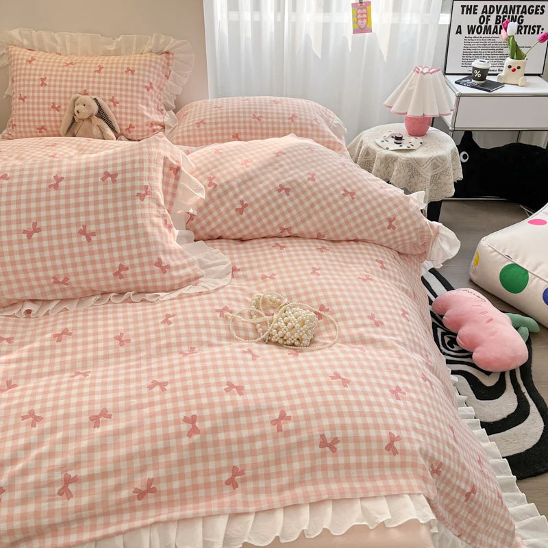 A pink and white gingham duvet cover set featuring ruffled fabric and floral embroidery on a bed.