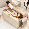A beige cosmetic bag is open, revealing various beauty products including a black tube and glass bottles.