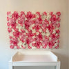 A wall panel covered in pink and white silk rose flowers displayed on a white shelf.