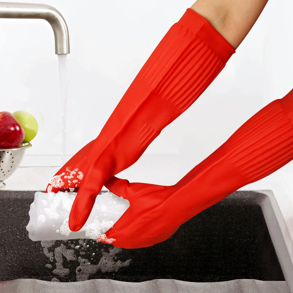 A pair of red silicone scrubbing gloves are shown cleaning a dish in a sink.