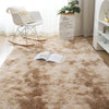 A fluffy beige rug is placed on a wooden floor in front of a white chair and a potted plant.