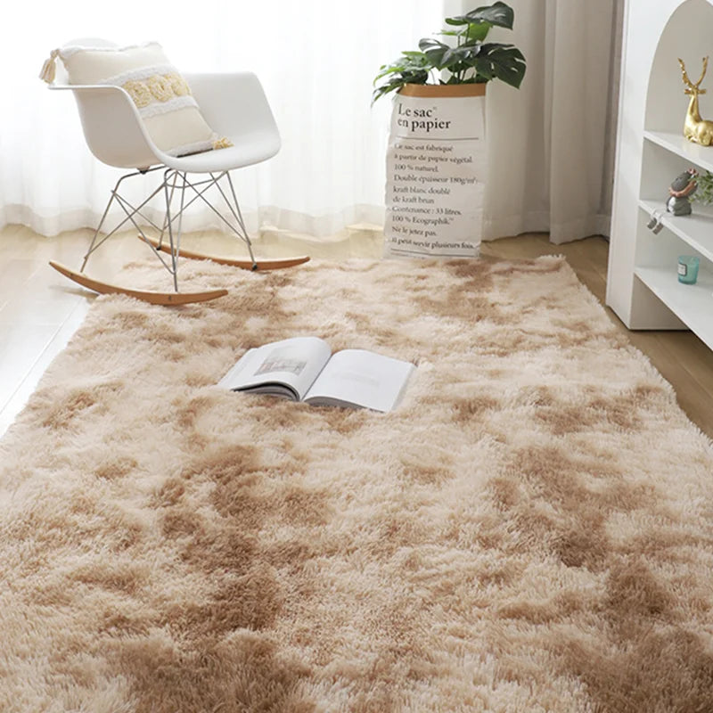 A fluffy beige rug is placed on a wooden floor in front of a white chair and a potted plant.