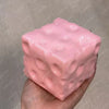 Pinkes Jumbo-Knetball ist in einer Hand vor einem hellgrauen Hintergrund gehalten.