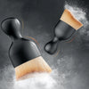 A black cleaning brush with soft bristles is shown dispersing white powder against a dark gray background.