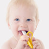 A baby is shown holding a yellow silicone banana-shaped teether and toothbrush.