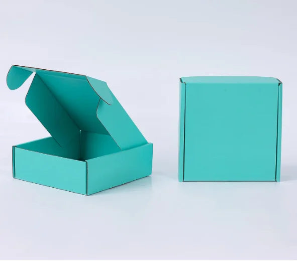 Eine tealfarbene Wellpappkartonbox, geöffnet und eine geschlossene Box daneben.