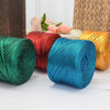 A collection of metallic flat ribbon yarn in shades of green, red, blue, and gold is displayed on a white surface.