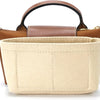 A light beige leather mini bag with a brown strap and wooden accents.