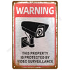 A vintage metal tin sign with a warning about video surveillance, featuring an icon of a security camera.