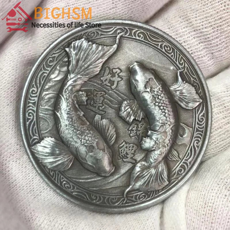 Silberner antikes chinesisches Koi-Glücksgeld mit Fischdesign, in der Hand gehalten.
