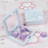 A box of silicone cat claw keycaps and several purple cat paw keycaps displayed on a pink background.