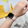 A hand wearing a pink silicone sport band on an Apple Watch, next to a yellow plate and some printed paper.