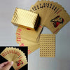 A stack of luxury gold foil playing cards and a wooden box with a checkered pattern.
