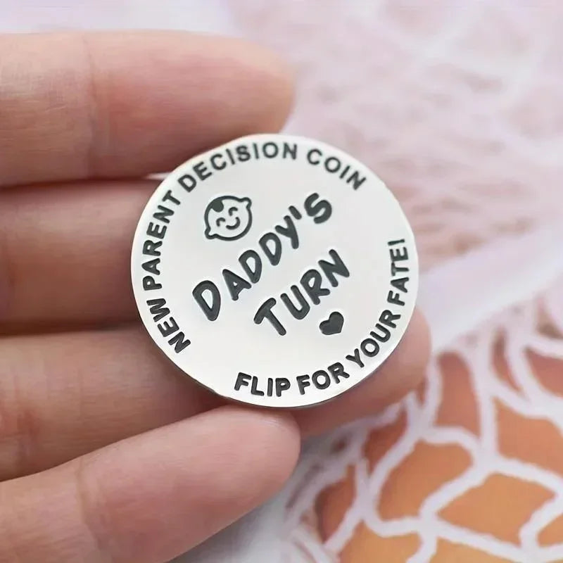 A round silver decision coin engraved with Daddy's turn for new parents