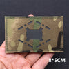A rectangular camouflage tactical patch with a national flag design and hook-and-loop backing is held in a hand.