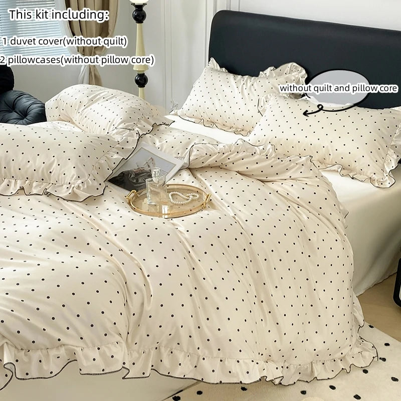 A set of three white bedding items including a duvet cover, two pillowcases, and a fitted sheet with black dot print fabric.