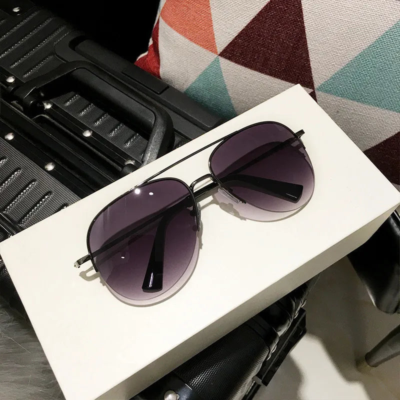 Ein Paar klassische Aviator-Sonnenbrille mit dunklen Linsen auf einer weißen Box neben einem schwarzen Etui.