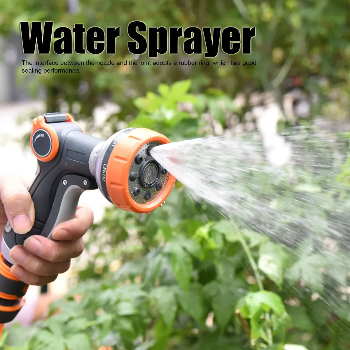 Una mano sostiene un pulverizador de agua para jardín naranja y negro, rociando una fina niebla sobre follaje verde.