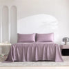 Luxuriöses Bambusbettlaken-Set in Mauve, drapiert über ein Bett mit weißen architektonischen Säulen.