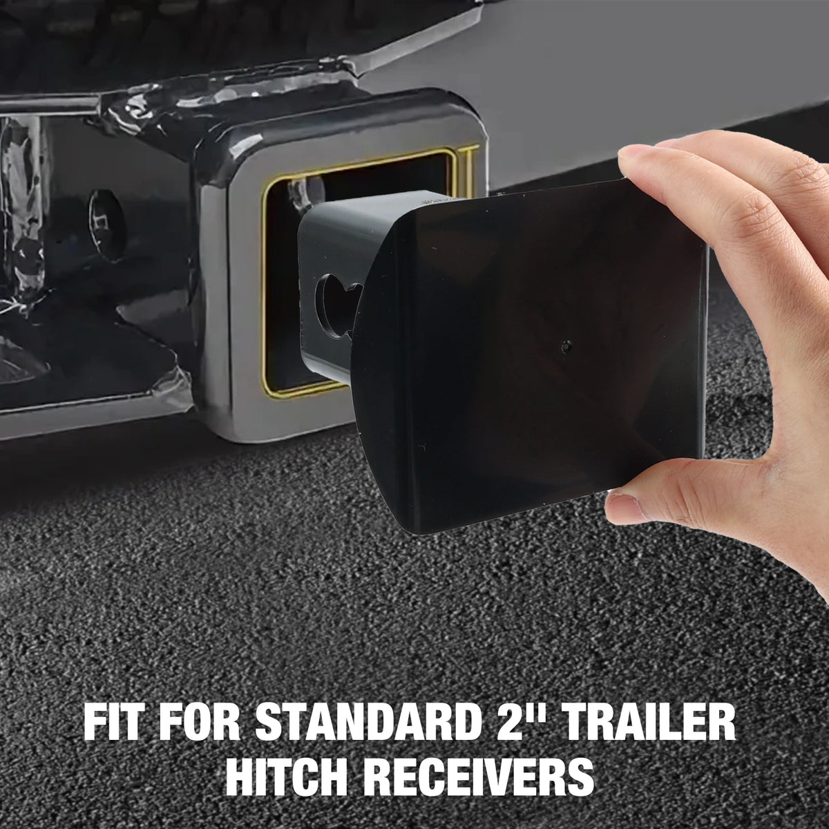 A hand is inserting a black plug cover into a silver trailer hitch receiver socket.
