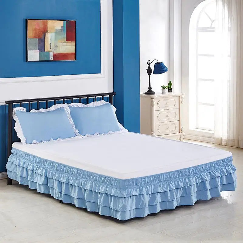 A white bed with a light blue elastic skirt and bedding in a modern bedroom setting.