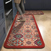 A rectangular rug with a floral pattern in shades of red, pink, teal, and beige is placed on a light wood floor.