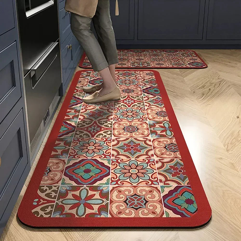 A rectangular rug with a floral pattern in shades of red, pink, teal, and beige is placed on a light wood floor.