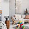 A cozy living room scene featuring a macrame curtain and a wooden bed frame with white bedding.