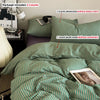 A set of green and white striped bedding includes a duvet cover, three pillowcases, and two pillowcases without inserts.