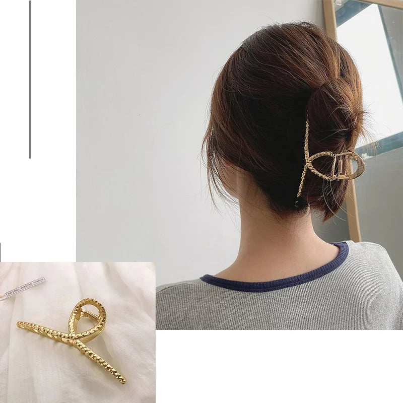 Nahaufnahme einer goldenen geometrischen Kreuz-Haarspange, die in dunklem braunem Haar einer Frau getragen wird.