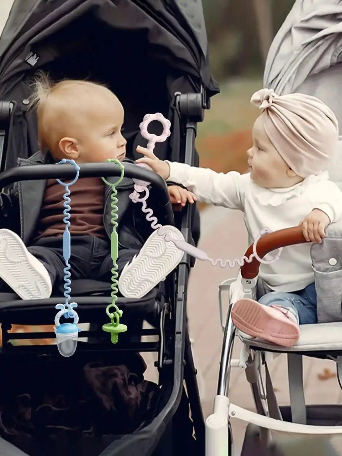 Two babies are shown using a silicone anti-drop pacifier clip with teether on their fingers.