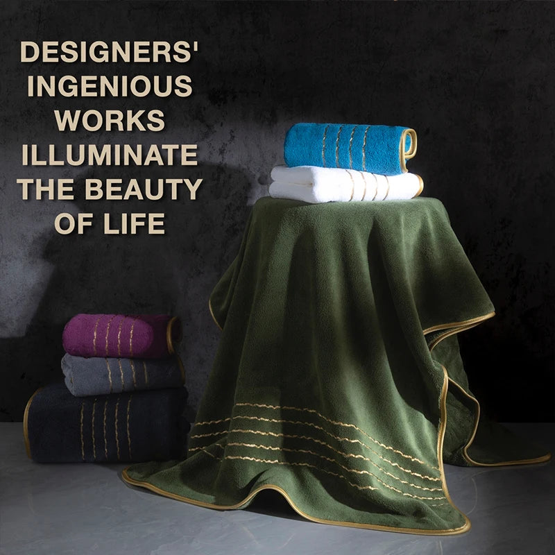 A stack of folded bath towels in teal, white, and purple rests on a dark green fabric drape with gold accents.