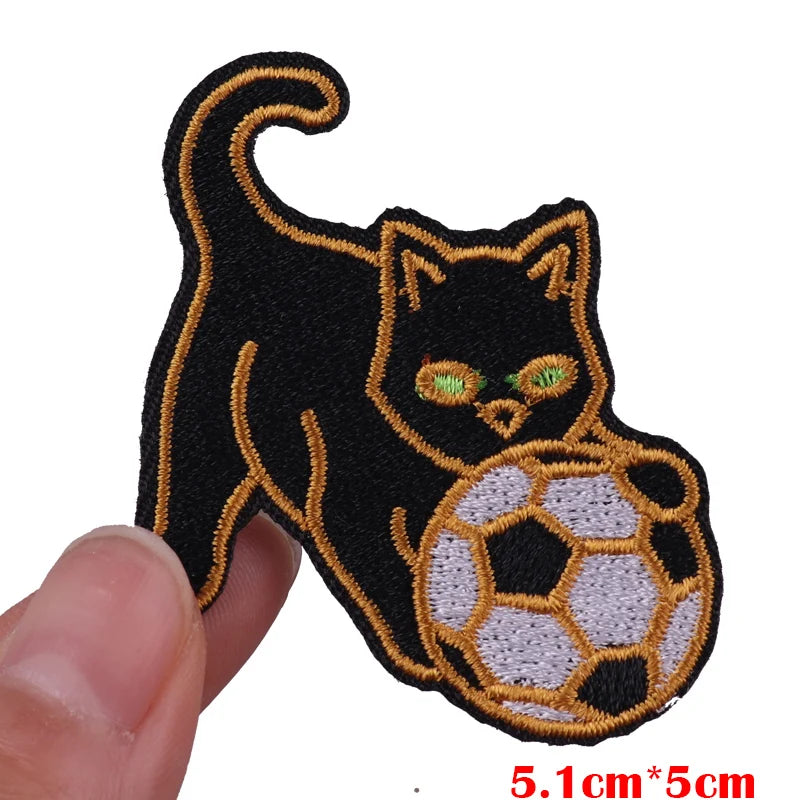 Black cat embroidered patch with glowing green eyes and a soccer ball design
