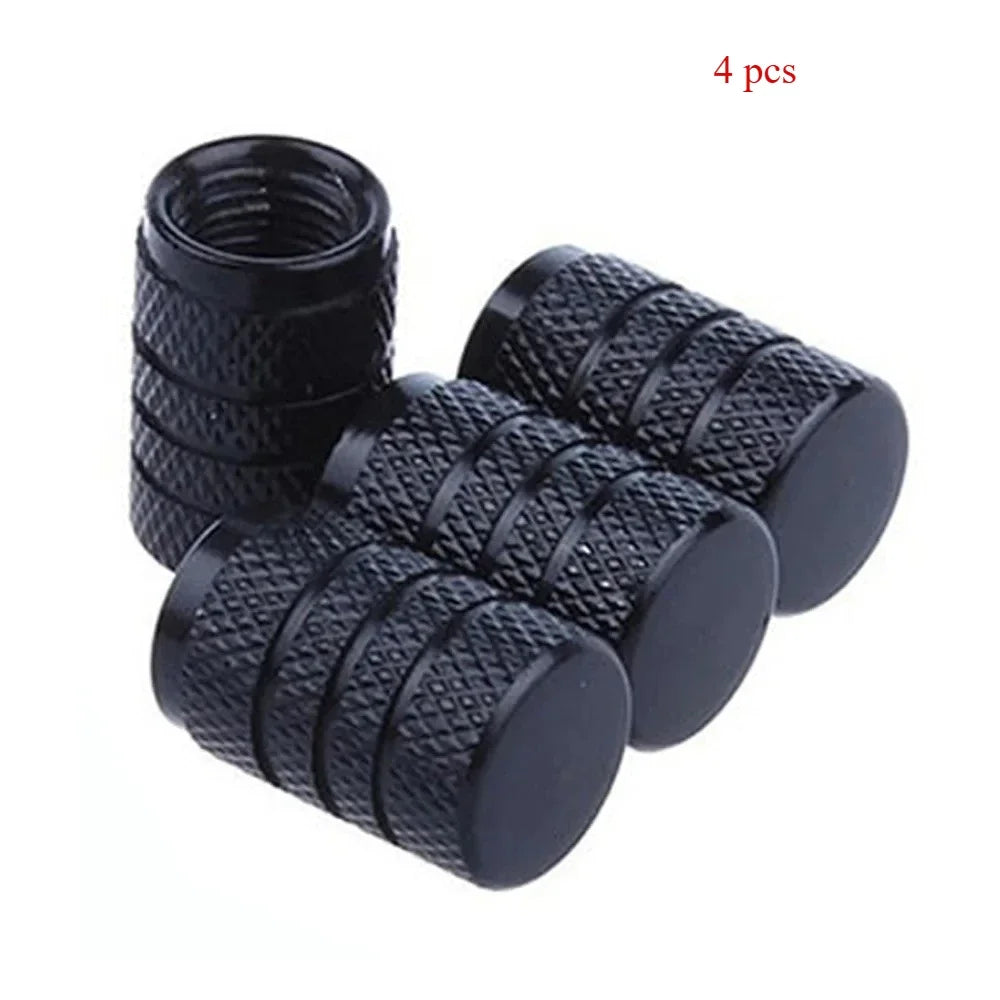 A set of four black knurled aluminum tire valve caps.