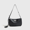 A black leather tote bag with a thin strap and a metal buckle hanging against a light gray background.