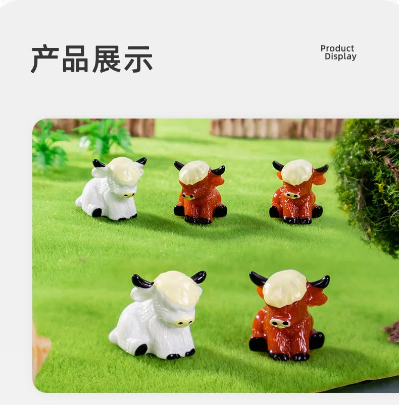 A display of four adorable resin Highland cow figurines in white and orange colors set against a green grassy background.
