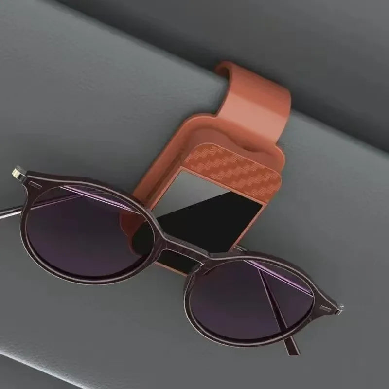 A pair of dark purple sunglasses resting in a magnetic holder designed for car sunshades.