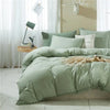 A light sage green duvet cover set with pom tassels on a bed, featuring soft microfiber bedding.