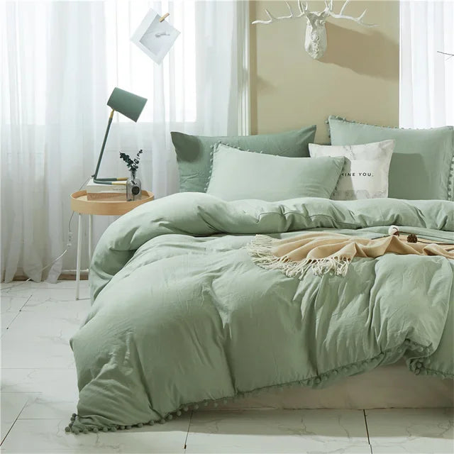 A light sage green duvet cover set with pom tassels on a bed, featuring soft microfiber bedding.