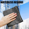 A hand holds a dark gray reusable microfiber cloth against a glass surface, demonstrating a waterless residue cleaning method
