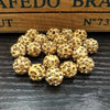 A pile of small, round, gold-colored crystal clay beads for jewelry making
