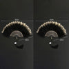 A pair of vintage folding fans with black feathers and golden lace trim shown against a dark background.