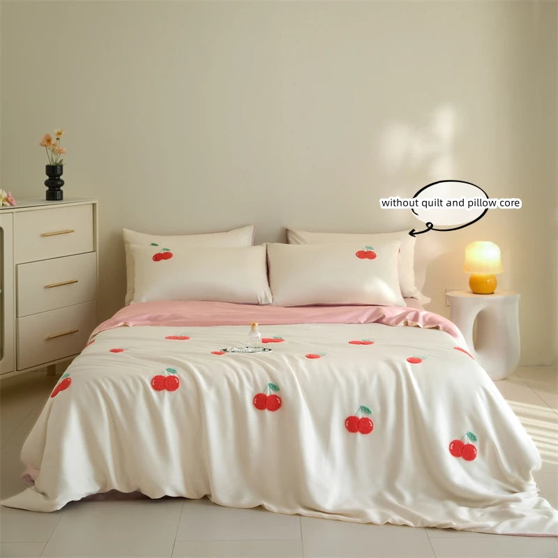 White embroidered duvet cover set with pink accents and pillows on a bed in a bright room.