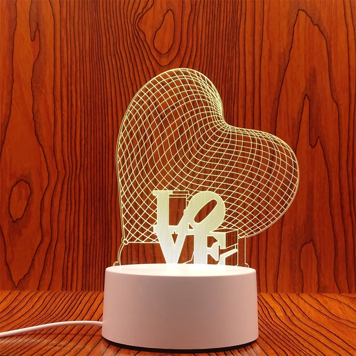 A clear wireframe heart sculpture light display on a white base.