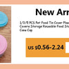 A set of three colorful silicone pet food tin covers or lids in green, yellow, and purple are displayed on a wooden surface.